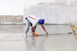 employee smoothing concrete floor using a broom by Bundaberg Concreters